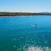Mare azzurro con paddleboarder sotto un cielo limpido.