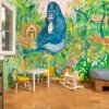 Stanza colorata con murale di giungla e gorilla, tavolino e sedia per bambini.