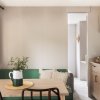Tavolo da pranzo con sedie nere accanto a un divano verde e cucina.