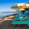 Una spiaggia con lettini verdi e ombrelloni gialli allineati lungo la riva.