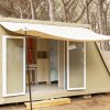 Una tenda moderna con apertura frontale in un bosco di pini.