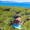 Vista aerea di una villa immersa nella vegetazione con piscina e vista sul mare.