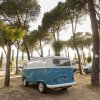 Furgoncino azzurro parcheggiato tra gli alberi del campeggio.