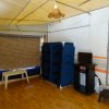 Interno di una tenda con mobile blu, piccolo televisore e pavimento in legno.