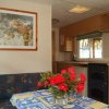 Cucina con tavolo apparecchiato e rose rosse, dipinto di natura morta appeso.