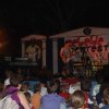 Concerto serale all'aperto con band sul palco e pubblico seduto.