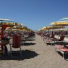 Ombrelloni gialli e blu con lettini a strisce rosse su una spiaggia sabbiosa.