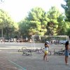 Ragazzi giocano a calcio in un campo all'aperto circondato da alberi.