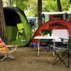 Due tende con sedie da campeggio e tavolo in un'area all'aperto tra gli alberi.