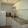 Cucina moderna con frigorifero, fornelli e lavabo, arredata con mobili bianchi.