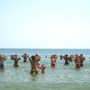 Gruppo di persone in acqua che sembrano fare esercizi sotto il sole.