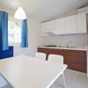 Cucina moderna con tavolo bianco, sedie, divano blu, e mobili in legno e bianco.