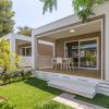 Modulo abitativo moderno con veranda, circondato da prato verde e piante.