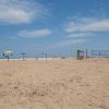 Una spiaggia di sabbia chiara con ombrelloni colorati e un campo da beach volley.
