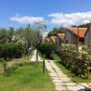 Bungalow con tetti rossi, affiancati da un vialetto lastricato e giardini curati.