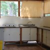 Cucina semplice con lavandino, fornelli e finestre coperte da tende gialle.