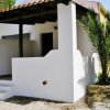 Bungalow bianco con veranda e pianta.