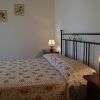 Letto matrimoniale con copriletto a fiori, comodini con lampade accese, decorazioni murali sopra.