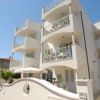 Un edificio bianco con balconi e dettagli architettonici eleganti, cielo blu sullo sfondo.