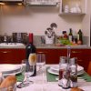 Una cucina con tavola apparecchiata e bottiglia di vino.