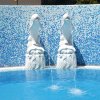 Scultura di delfini su sfondo di piastrelle blu.