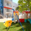 Gioco per bambini con altalena e scivolo su prato.