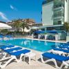 Piscina all'aperto con lettini blu e ombrelloni bianchi, accanto a edifici moderni.