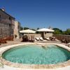 Piscina circolare con lettini e ombrelloni.