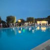 Piscina illuminata con palloncini galleggianti e persone sullo sfondo.