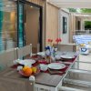 Tavolo apparecchiato su una terrazza con lettini in fondo.