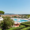 Piscina con ombrelloni e campagna intorno.