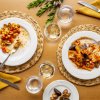 Due piatti di pasta con frutti di mare su una tavola apparecchiata. Bicchieri e posate visibili.