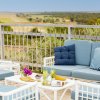 Sala con divani blu e tavolino su una terrazza con vista panoramica su campi e alberi.