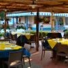 Area ristorante all'aperto con tavoli apparecchiati in giallo e blu, con chiosco sullo sfondo.