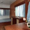 Interno di una roulotte con letti, fiori su un tavolo.