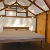 Roulotte con letto matrimoniale e tende arancioni in una struttura in legno.