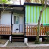 Piccolo bungalow con veranda e tende verdi a righe.