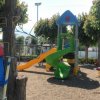 Parco giochi con scivoli colorati e casetta a fungo.