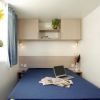 Camera da letto con letto matrimoniale, un laptop e giornali sul letto.