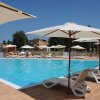 Piscina all'aperto con sedie a sdraio e ombrelloni bianchi.