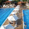 Due piscine affiancate con persone che nuotano e si rilassano sotto gli ombrelloni.