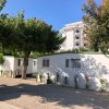 Due case mobili bianche con aiuole, alberi attorno e un edificio sullo sfondo.