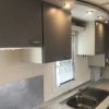 Cucina moderna con pensili grigi, lavabo in acciaio e una finestra.
