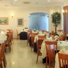 Sala da pranzo raffinata con tavoli rotondi e sedie in legno, decorata con fiori.