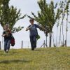 Due bambini corrono giù per una collina erbosa con alberi sullo sfondo.