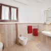 Bagno moderno con piastrelle beige, lavabo, bidet e due asciugamani rossi.