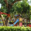 Parco giochi con altalena e scivolo colorato tra gli alberi.
