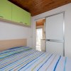Camera da letto con armadio verde e letto con copriletto a righe.
