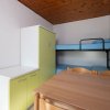 Letto a castello, armadio verde e tavolo di legno.