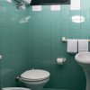 Bagno con piastrelle verdi, wc e lavandino.